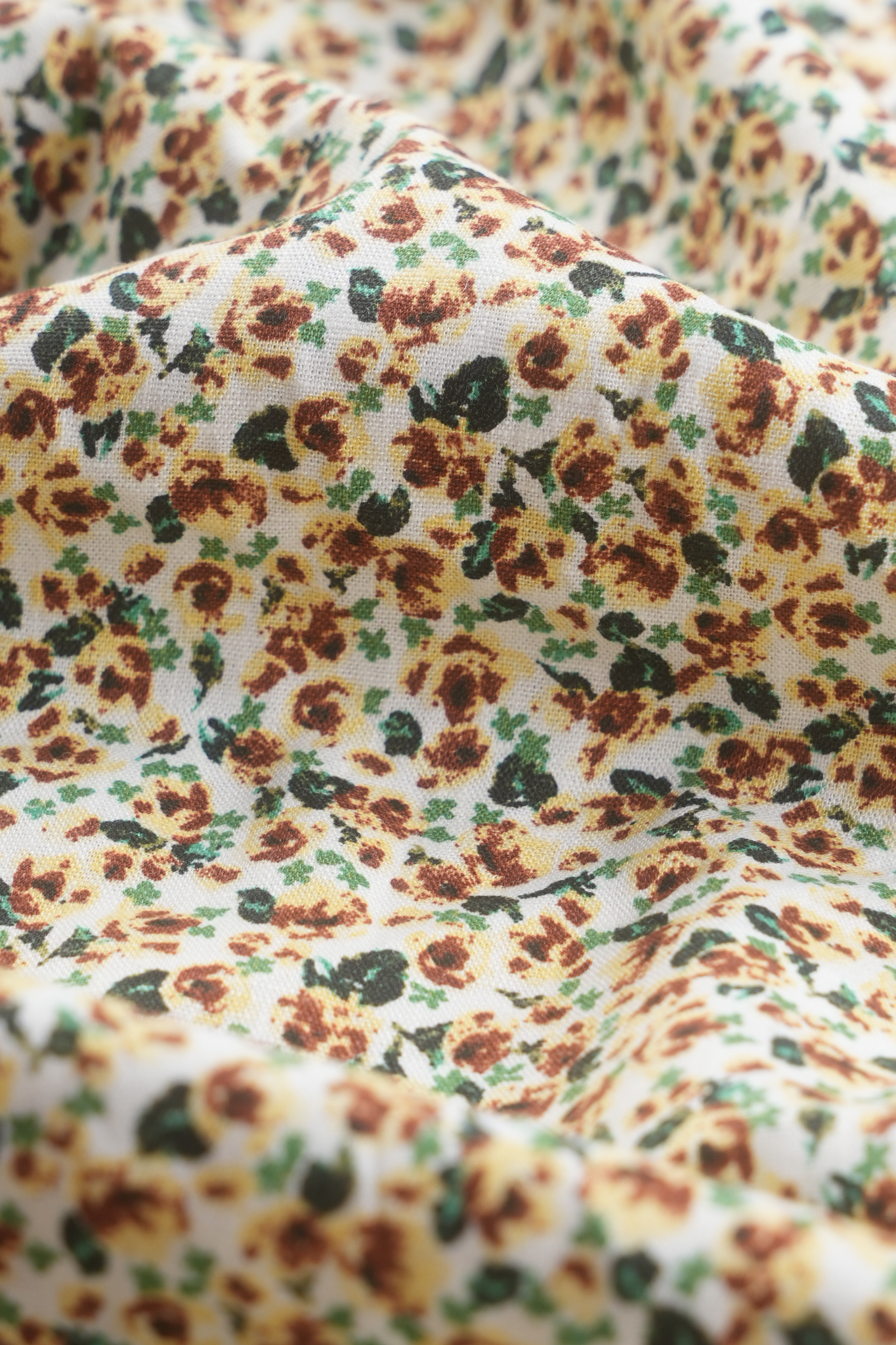 This is a close-up photo of the fabric of The Cascade Skirt. It is made of a luxurious cotton-linen blend, is 100% machine washable, and has a beautiful pastel yellow and green floral print.