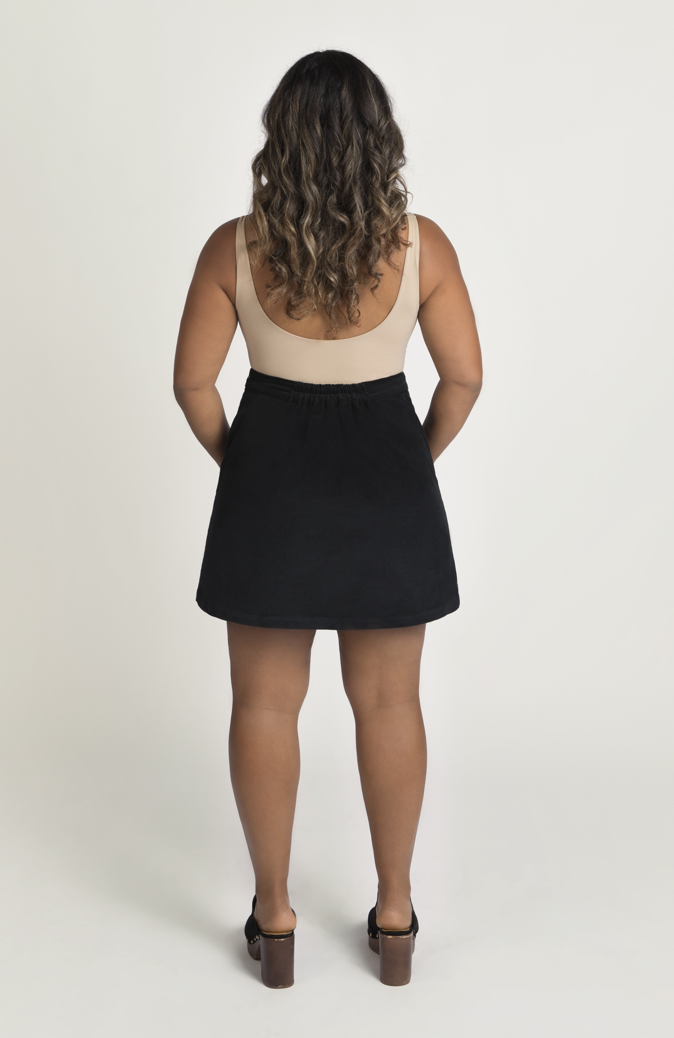 The Cord Mini Skirt by Aam The Label has a redesigned waist-to-hip ratio that is made for women with pear and hourglass shapes. Shown here is the full back view in classic black.