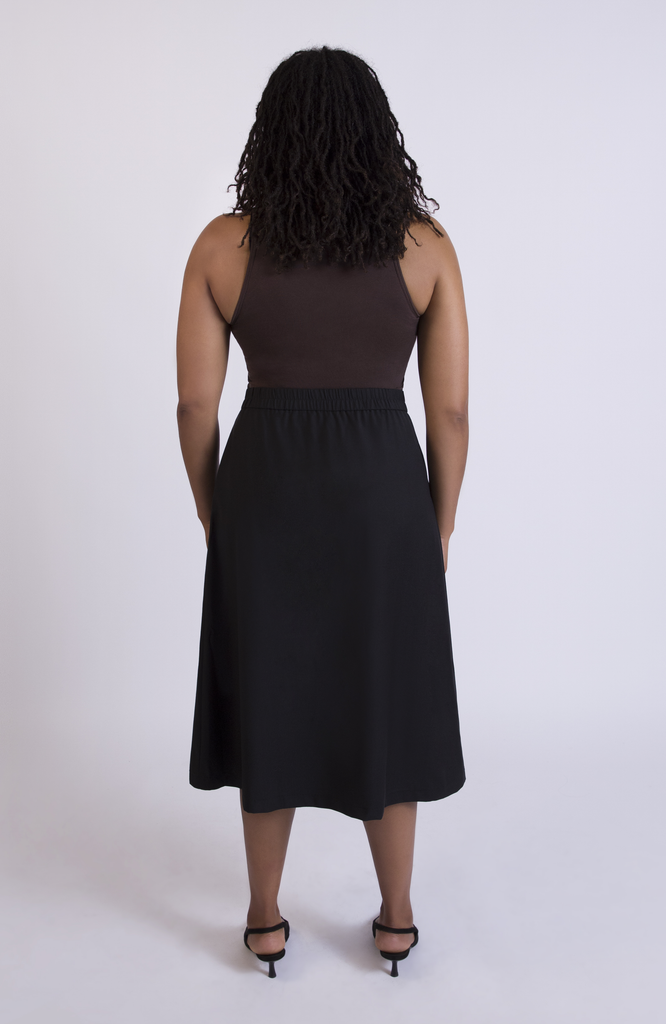 The Wool Midi Skirt by Aam The Label has a discreet back elastic that provides comfort at the waist and eliminates waist gaps. Shown here in Black.
