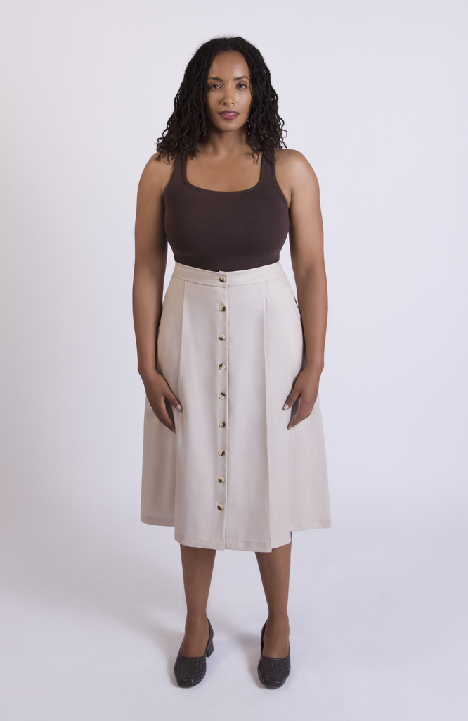 The Wool Midi Skirt is a gorgeous A-line skirt that sits snug at the high waist with a loose, flowy drape through the seat, comfortably accommodating full hips and thighs. It has a center button closure and two thin pleats for movement. Shown here in a gorgeous Oat color.