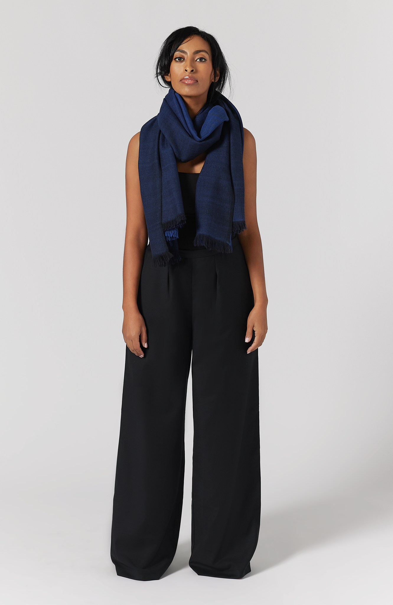 The Aurora Wrap by Aam The Label is a soft, warm 100% merino wool wrap that can be worn as a scarf or a shawl. It has been handwoven and is reversible. Here you can see the midnight color wrapped as a scarf.