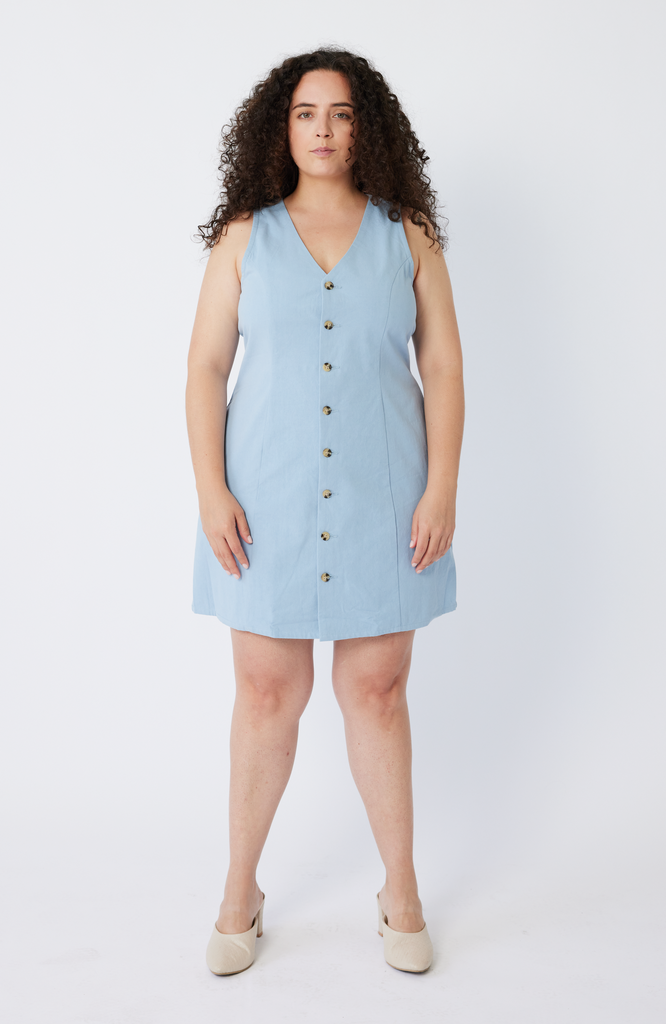 The Everywhere Dress is made for pear and hourglass shapes. Designed to slim through the waist with a roomy fit for full hips and thighs. It's mid-thigh length with a front button closure and is ethically made from 100% organic cotton. This is The Everywhere Dress in 
sky blue.