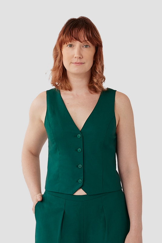 The Wool Vest by Aam is a chic, cropped vest that pairs perfectly with high waisted trousers. The vest is made from a warm, 96% wool with 4% elastane and is fully lined with organic cotton for a smooth finish on the skin. Shown here is a close-up of the vest in a stunning emerald green color.