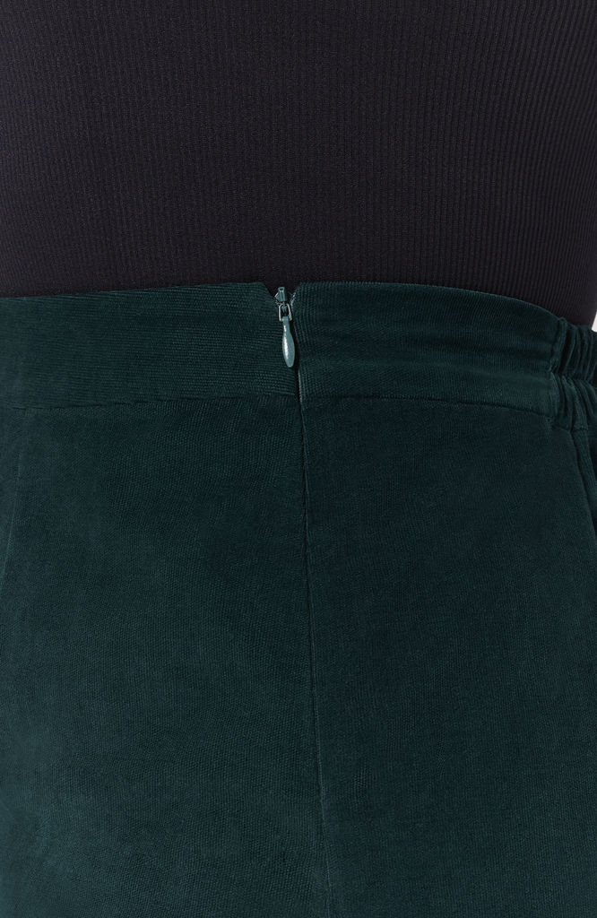 The Cord Mini skirt has hidden zipper closure for ease of wear and a seamless finish. Shown here in a tone on tone, deep, forest green shade.