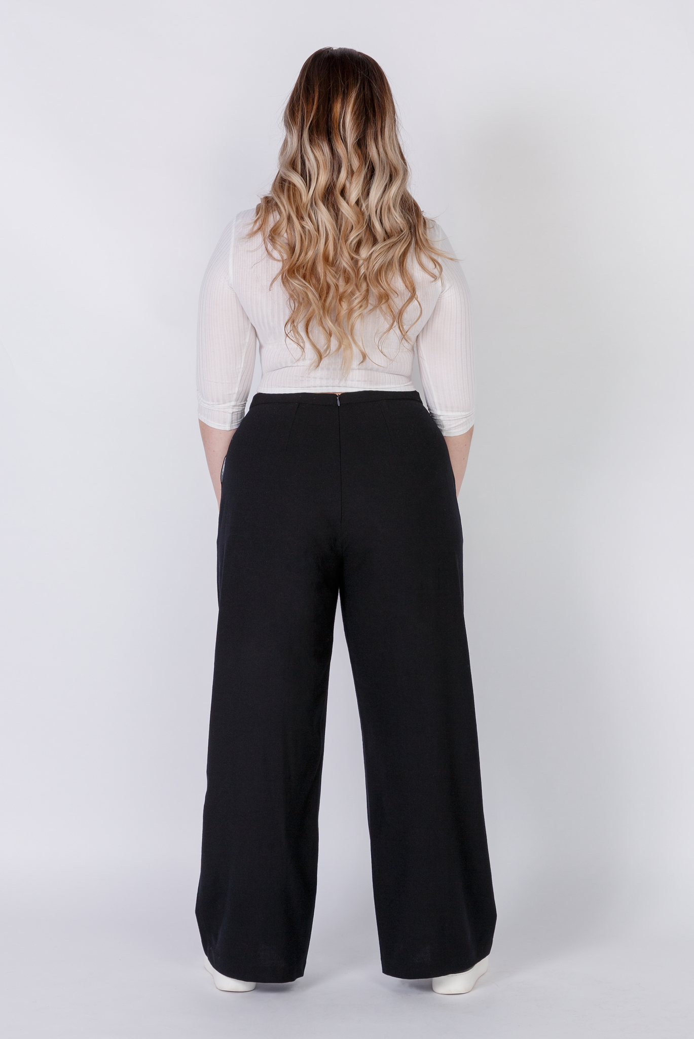 The Limited Edition Wool Wide Leg Pant by Aam is made for women with full hips and thighs. This is the back view of the pant, which shows the fit at the waist, hip and thigh. The pant comes in two colors - black (pictured here) and grey.