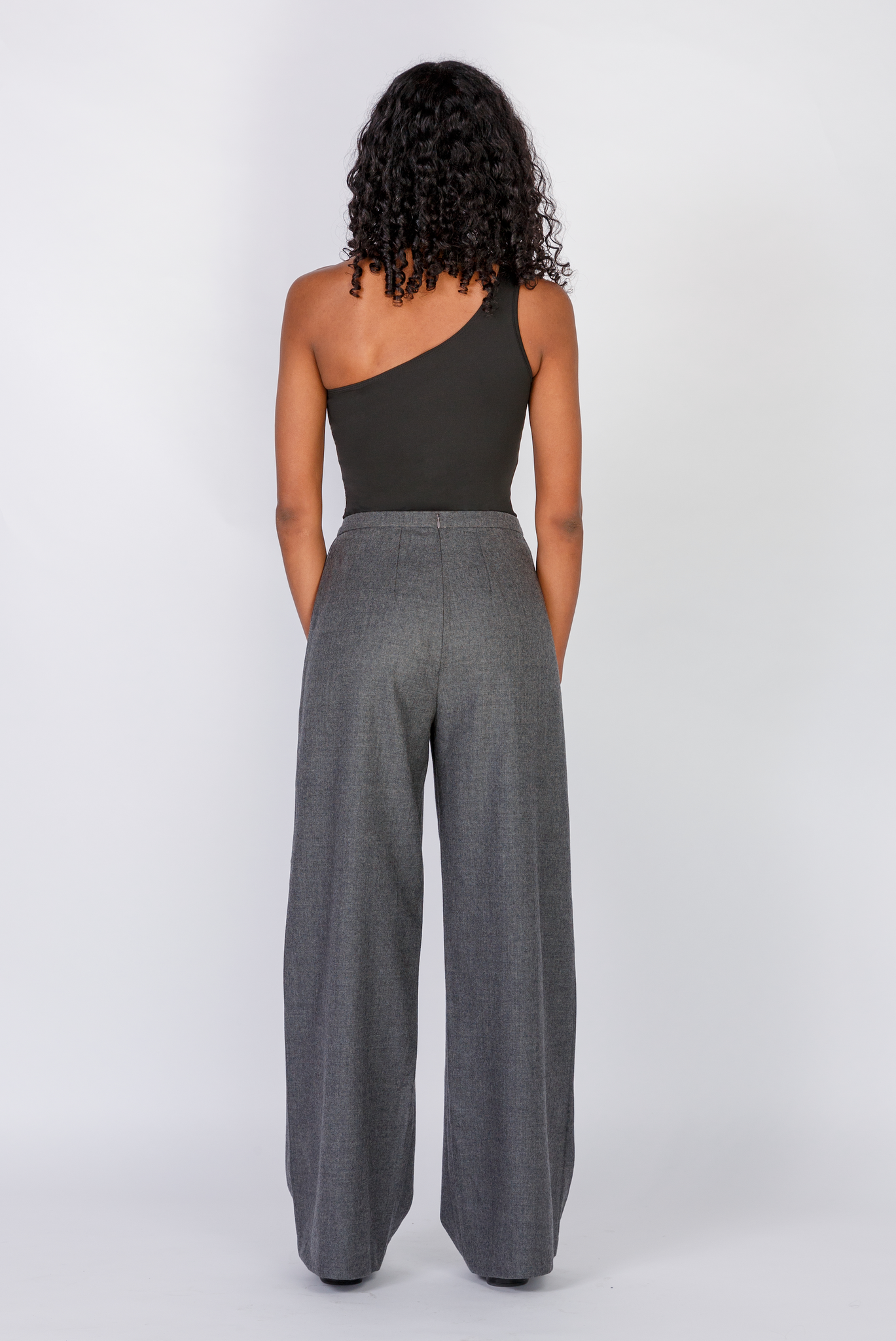 The Limited Edition Wool Wide Leg Pant by Aam is made for women with full hips and thighs. This is the back view of the pant, which shows the fit at the waist, hip and thigh. The pant comes in two colors - grey (pictured here) and black.